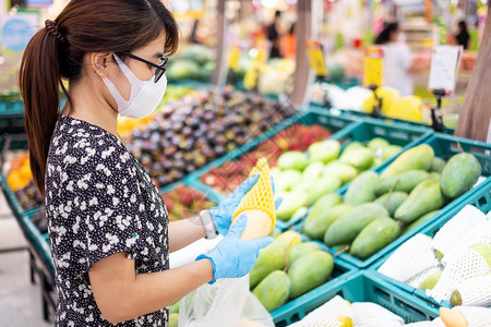 顾客健康或者亚裔妇女佩戴硝化子手套在超市或杂货店里持有成熟的芒果保护阴阳渗透卫生新正常和19大流行后的生活图片