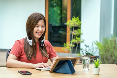 在职的初创公司禁止亚洲商业妇女使用带有键盘和耳机的技术平板和键盘及耳机在户外家庭花园创业和企主社会距离和自我责任等在家工作时使用图片