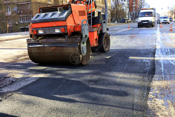 运输路中央沥青表面修补的热沥青在晴明阳光朗的一天公路上要修理的重振动道路滚压干线上的沥柏油以及滚轴肮脏的图片