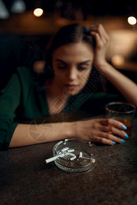 饮料一种在酒吧柜台坐着的醉累妇女一位在酒吧人情闲暇活动抑郁症醉妇女在酒吧柜台抽根烟一个女在酒吧奢华图片