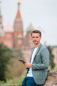 镇在圣巴西尔斯教堂和克里姆林宫肖像背景上有电话户外的青年男子莫斯科快乐城市青年男子欢乐在欧洲市商人的克里姆林宫肖像游客图片