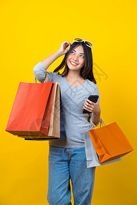 淑女带着一个满购物的包手机和墨镜在孤立黄色背景上买东西复制空间和工作室黑星期五季节销售概念c带黄色的亚洲人图片