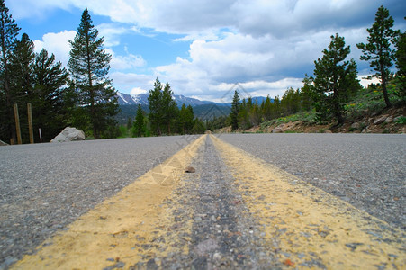 落下冬天黄色的在明亮春天地平面在山路中间俯视着高山的道路天空通向狂野的光明蓝天路上有几朵乌云图片