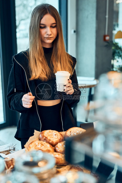 脸柜台女人拿着杯子喝咖啡看着糕点面包蛋和饼干等待命令女孩购买甜食和热饮让在咖啡店买东西的年轻女青可以休息去白种人图片