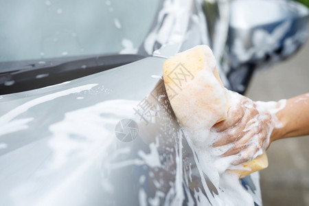 雨刮器清洁剂持有手黄色海绵和泡沫清洗窗的工人男子手持黄海绵和泡沫洗车用擦玻璃窗户灰色的背景图片