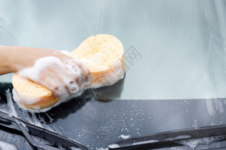 肥皂水反射持有手黄色海绵和泡沫清洗窗的工人男子手持黄海绵和泡沫洗车用擦玻璃窗户清洁剂图片
