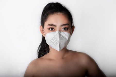 白色的身戴医用面罩亚洲年轻女近身穿上医疗面具N95以保护免受空气呼吸道疾病如灰色背景的流感共食19PM25粉尘和烟雾安全感染概念图片