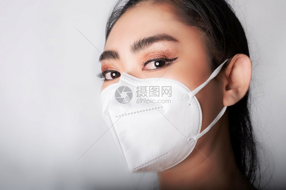 身戴医用面罩的亚洲年轻女近身穿上医疗面具N95以保护免受空气呼吸道疾病如灰色背景的流感共食19PM25粉尘和烟雾安全感染概念年轻图片