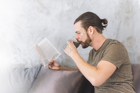 白色的复制宁静长胡子男的肖像喝着热咖啡和阅读书在节假日放松嬉皮士男享受茶时间坐在沙发上休闲咖啡店里的生活风格图片