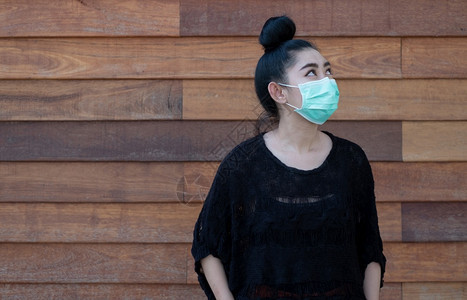 优质的流行病老穿戴医疗面罩以防止呼吸道疾病的亚洲美丽年轻女青妇如在壁木背景上染19PM25型流感粉尘和烟雾女安全感染概念图片