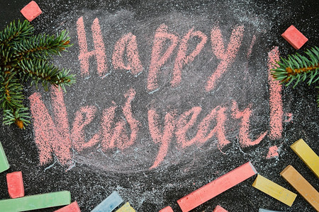 新年快乐背景或明信片新年写粉笔在学校董事会上写着礼物模拟板装饰有壁画树枝的圣诞节穿木板图片