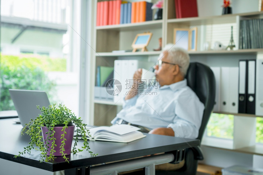 坐在笔记本电脑前的亚洲老人他坐在椅子上放松老人仍然可以工作对社会做出判决隔离人类免疫系统体休息在职的坐着图片