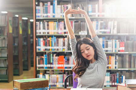 各种样的在大学图书馆或群落里阅读和做功课的亚洲青年学生在书架上木制桌子的各种书籍和文具上写着返回学校的书架知识人们图片