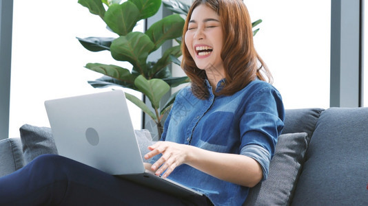 快乐的数字在家工作参加庭办公室膝上型电脑在线会议的妇女使用笔记本的企业家女商妇坐在沙发技术上新的正常生活方式快乐女人打键盘手提电图片