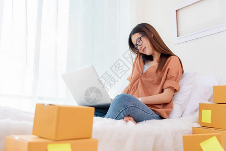 在线的国内互联网使用手提笔记本电脑和在床上打话的亚洲美女妇商业和技术概念交付和在线购物概念邮政和服务主题图片