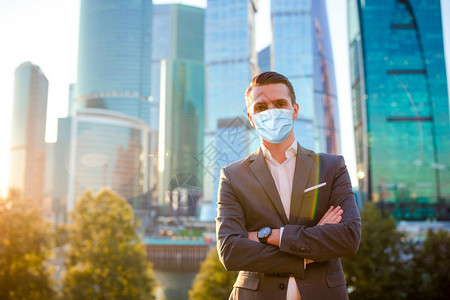 身戴防面具的人在城市里戴着面具防止在幕后有摩天大楼的幕后建筑商人一边站在玻璃摩天大楼旁边看着复制空间雇主企业家聪明的图片