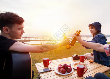 一群亚裔朋友在日落时湖附近露营旅游饮酒啤弹吉他与夏月快乐一起欢男人马克杯咖啡图片