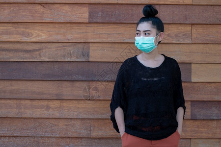 空气穿戴医疗面罩以防止呼吸道疾病的亚洲美丽年轻女青妇如在壁木背景上染19PM25型流感粉尘和烟雾女安全感染概念药物保护的图片