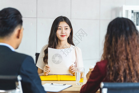 年轻亚洲女毕业生持有简历文件准备在开始面试之前与两名经理进行工作面试并在会议室提出积极动Business雇用新会员概念Busin图片