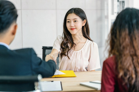 办公室成功的就业年轻亚洲女毕生与两名经理握手在开始面试前欢迎两位经理在会议室进行积极动的工作面试Business雇用新会员Job图片