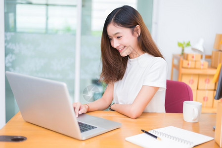 亚洲女在办公室商业营销和兼职概念中使用笔记本电脑和互联网时享受生活在网上购物和商业成功主题上愉快地做工作乐的心情邮政专业卖图片