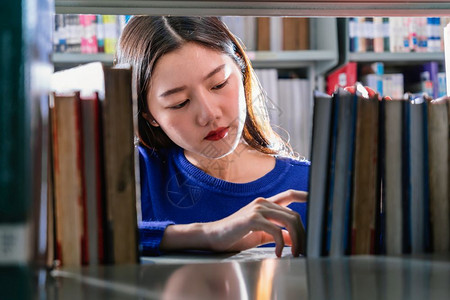 青年学生在书架上找寻书籍图片