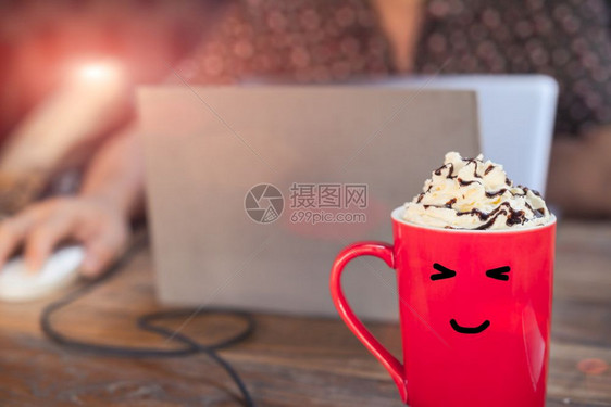 巧克力甜点糖红杯热摩卡咖啡在木桌上面带微笑的脸用笔记本电脑与工人一起作图片