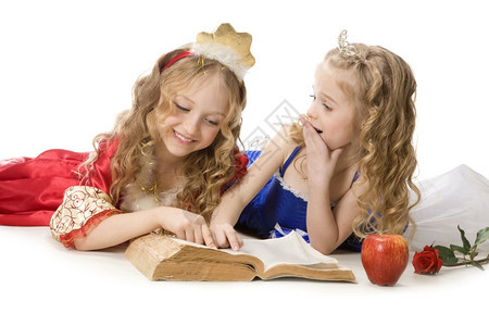 颜色仙女苹果两个美丽的小姑娘穿着公主服装的金发长头穿着公主服装在白色背景上读一本魔法书红色和蓝帝国礼服红和蓝色帝国礼服连衣裙高清图片素材