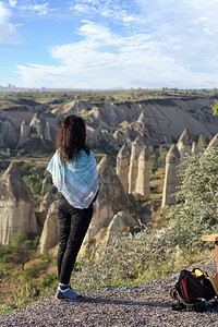 砂岩户外肩膀一只年轻女孩站在悬崖边缘看着山峰峡谷和卡帕多西亚的蓝天空一个年轻女孩站在悬崖边缘看着地平线卡帕多西亚山谷和蓝天Cap站立高清图片素材