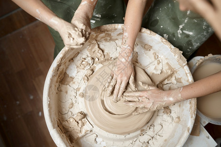 车轮男生手工业儿童在讲习班的陶艺者股轮上工作手顶高视距Clay在艺术学校做模范课青年民间工艺大师爱好童年快乐儿在陶艺者股轮上工作图片