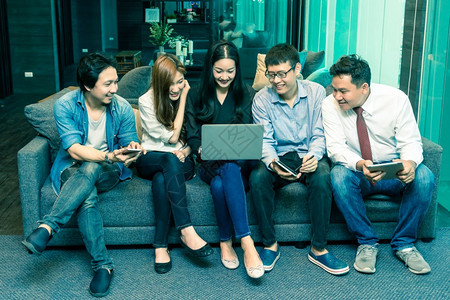 使用技术移动平板笔记本电脑和计算机在现代办公室工作或社交网络上临时穿便衣的亚洲工商集团人业体概念在现代办公室中会议墙幸福图片