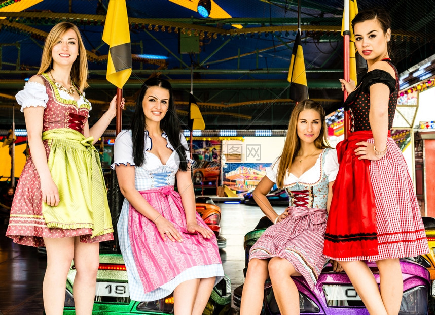 在德国FunfairOktoberfest和传统的dirndl礼服和保镖车背景的德国风乐Oktober节上两个非常典型的德语女孩图片
