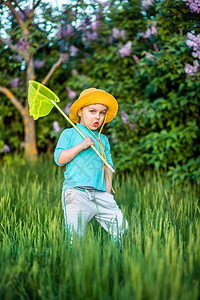 一个迷人的孩子在温暖和阳光明媚的夏天或春在草地上玩勺子孩们积极休息男孩很有趣喜欢蝴蝶和错误一个迷人的孩子在温暖和阳光明媚的夏天在图片