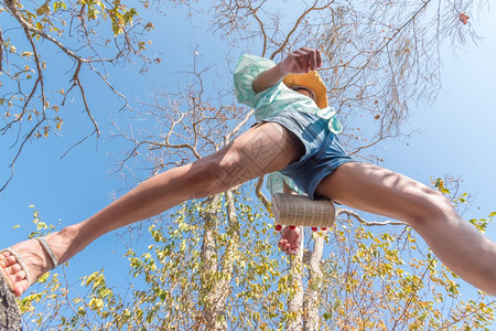 成就极端低角度观察感女短牛仔裤中空跳跃跨过摄像头在森林下拍摄概念旅行积极生活方式克服障碍方面树上和天空高架的概念旅行妇女跳跃或越图片