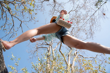 自由速度未来低角观察感女短牛仔裤中空跳跃跨过摄像头在森林下拍摄概念旅行积极生活方式克服障碍方面树上和天空高架的概念旅行妇女跳跃或图片