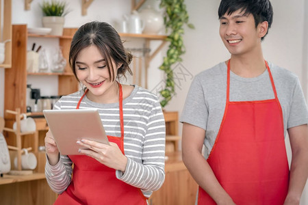 男朋友幸福的亚洲情人或侣以幸福行动做饭通过社交网络在现代房子夫妻和生活方式概念的厨房室里用技术平板电脑烹饪屋早餐图片