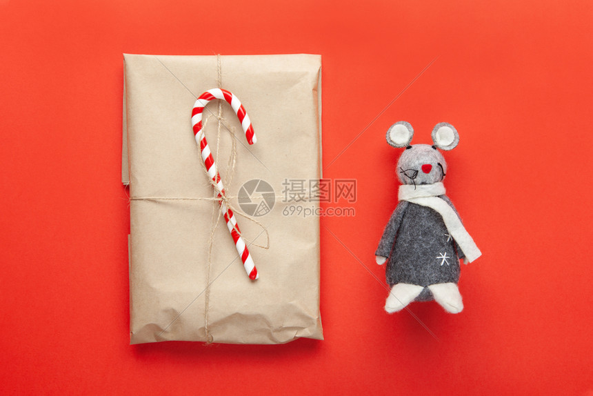 灰色玩具老鼠在日历上标有20年的标志圣诞礼物包装在手工艺纸上用甘蔗糖装饰在红色背景上最起码的风格极简主义圣诞节棒糖图片