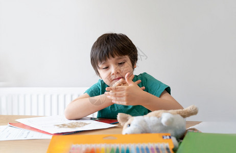 保持学校在家工作独自做功课的学童肖像男孩拿着棕色笔画和在白纸上写桌子小学和家庭教育概念上的白纸写作图片