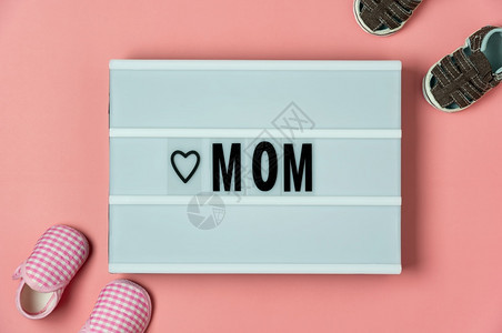 甜的单词欢乐母亲节假日背景概念Flat平铺婴儿鞋和MOM在家庭办公室书桌式口音创意设计上关于现代美丽粉色纸的文字载于MOM粉彩图片