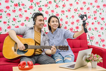电话视频麦克风亚洲Vlogger已婚夫妇播放音乐并通过手机社交媒体渠道情侣和人节vlog和影响者自由职业概念通过手机向与会者直播图片
