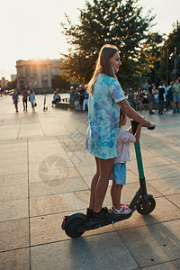 出租闲暇年轻少女和她妹的学龄前女孩在市中心骑电动摩托车家庭快乐的人概念真实时刻情况Y我踢图片