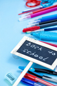 统治者最佳返回学校概念笔记本和学校用品笔记本苹果书签笔薄饼剪刀脚笔蓝红黑和白色蓝背景图示纸图片