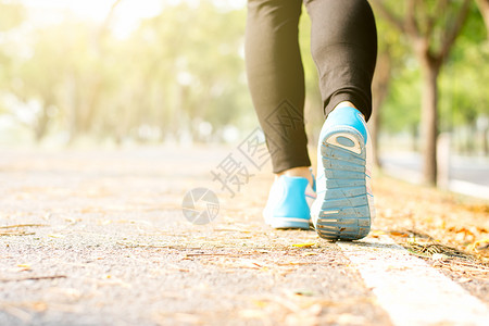 跑步健身女的腿正跑在街上公园里周围都是大自然早晨阳光照耀右脚聚焦着她的锻炼冥想图片