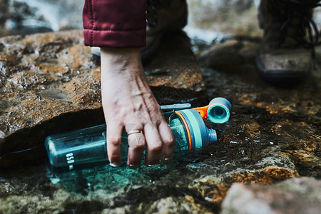 游客在爬山时用纯净的水瓶装河流里的水图片