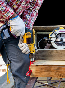 家男木制匠钻一个洞入木板的上并用电带闭导钻孔以配合在一起的爆屁股工具和设备用于木工概念专业的拧紧图片
