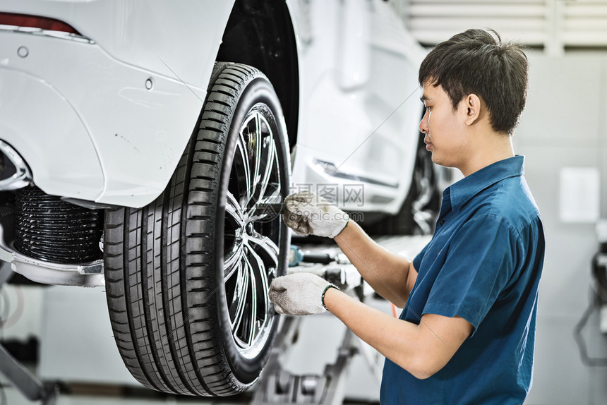 齿轮或者胎维修服务中心保养的亚洲机械技工检查和修理车轮该中心是客户汽车修理和维护概念的展示室技术员或工程师专业作的一部分为顾客汽图片