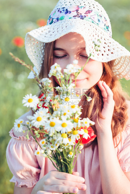迷人的在野花田中美丽年轻女孩少在草原上采春花拿着束她戴帽子和夏衣与自然相近的时光中度着穿帽子和夏服父母亲图片