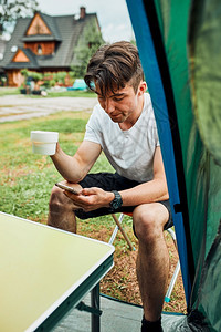 食物马克杯年轻人喝着咖啡坐在帐篷前早上的青少年在暑假周末旅行期间享受自由时青年男子喝着咖啡早上坐在帐篷前男孩喝着咖啡徒步旅行者图片