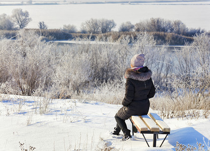 景观场地女士一位年轻子身处冬天的光线下太阳升起迎接南虫河岸黎明的曙光坐在木板凳上望着距离一位年轻女子坐在木板凳上看着阳光明媚的冬图片