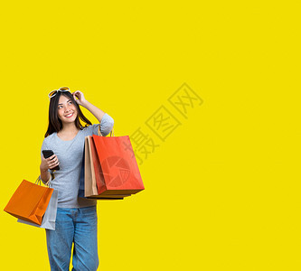 笑购买顾客带着一个满购物的包手机和墨镜在孤立的黄色背景上复制空间和工作室黑色周五销售概念blackFridayfirebreat图片